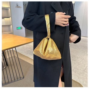 Sac à bandoulière chic à paillettes dorées porté avec un manteau noir pour le dîner