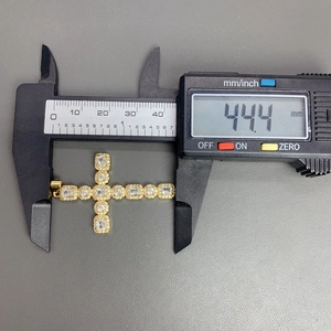Macro view showing measurement of a gold cross pendant with cubic zirconia stones