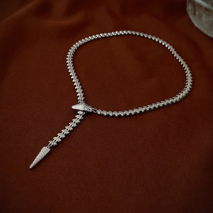 Detailed shot of silver Y-shaped snake chain necklace with conical pendant on dark fabric