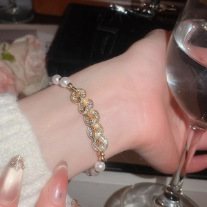 Detailed close-up of a pearl and gold zircon bracelet worn on a female wrist in elegant setting