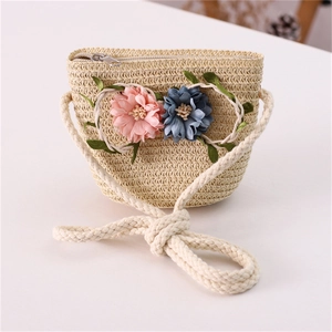Detail of a straw woven girl's bag featuring pastel fabric flowers and a thick rope strap