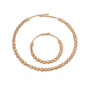 Set di gioielli con collana e bracciale a perline dorate a forma di cuore su bianco