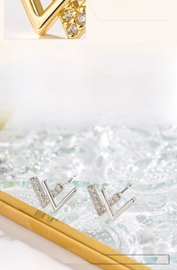 Macro detail of V-shaped silver earrings featuring micro-set zircon stones and polished finish