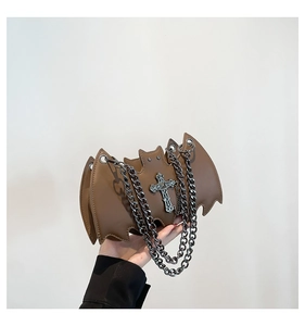Close-up of brown bat-shaped leather bag with silver cross and chunky chain strap