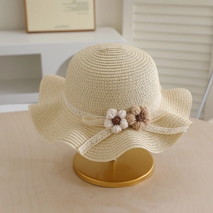 Close-up of wavy brim straw hat with lace trim and handmade crochet flower details