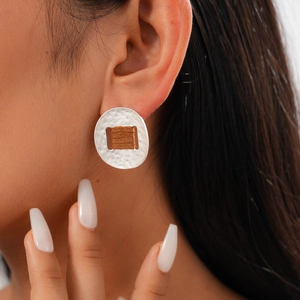 Silver round earrings with hammered texture and brown cord wrap shown on model