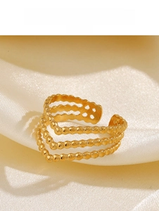 Macro view of triple-layered gold beaded V-shaped ring on elegant beige satin fabric