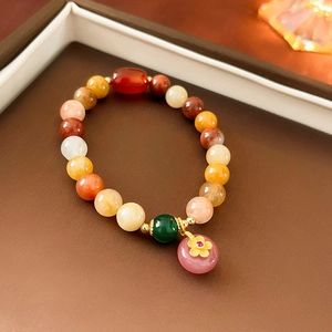 Detail of beaded gemstone bracelet with red agate and flower charm in velvet box