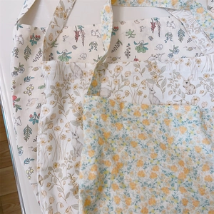 Detail of floral and rabbit prints on cream cotton canvas tote bags in a soft aesthetic