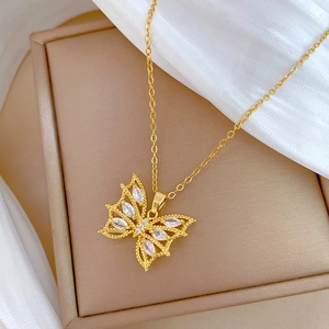 Gros plan du pendentif papillon doré avec zircons marquise et fine chaîne croisée