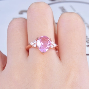 Rose gold pear shaped pink diamond engagement ring with side accents on hand