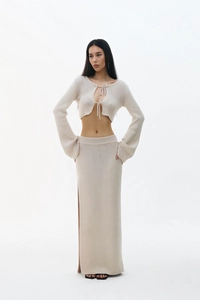 Détail d'un ensemble en tricot crème avec haut à nouer à manches longues et jupe fendue