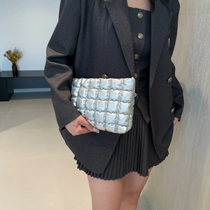 Pochette matelassée argentée à motif nuage tenue par un mannequin en costume décontracté