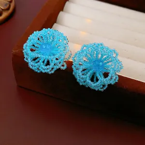 Blue beaded flower stud earrings with crystal center on a luxury jewelry box display