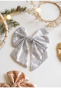 Close-up of sparkling silver sequin Christmas bow decoration on festive pine background
