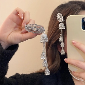 Detail of ethnic silver hair clip with tassel bells and sparkling rhinestones on hair
