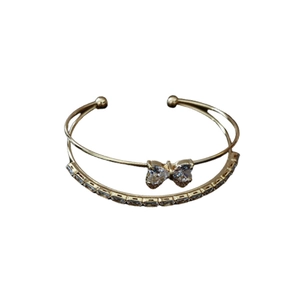 Golden double-layered open bangle featuring a sparkling cubic zirconia bow centerpiece
