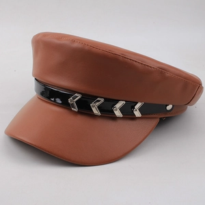Detail view of brown leather baker boy hat with black patent band and silver accents