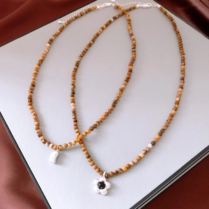 Détail de colliers bohèmes avec perles brunes, pendentifs fleur et perle irrégulière