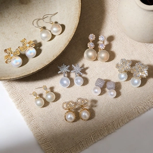 Macro shot of pearl earrings with cubic zirconia and bow motifs on linen background