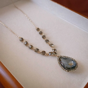Luxurious gold necklace with gray teardrop pendant and crystal halo in a jewelry box