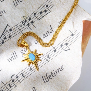 Macro shot of gold sunburst necklace with blue opal stone on vintage sheet music