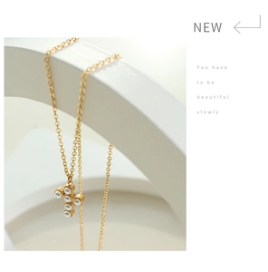 Detailed view of a gold cross pendant necklace with six elegant white pearls on a chain