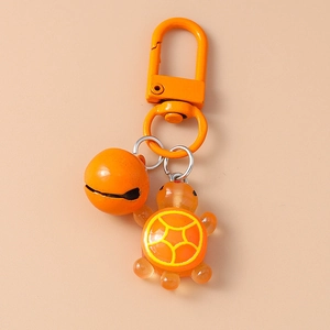 Detailed view of an orange resin turtle keychain with a metal bell and swivel hook clasp