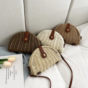Detail of four handmade straw crossbody bags in various colors on a white bed sheet