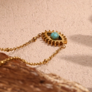 Close-up of 18K gold plated evil eye pendant necklace with turquoise bead on rustic wood