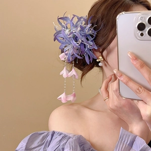Détail d'une pince à cheveux fleur en tissu violet avec pompons et perles