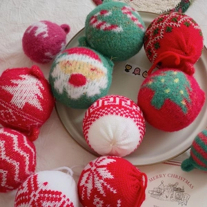 Knitted Christmas tree ornaments with festive red and green patterns on a ceramic tray