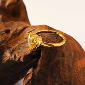 Macro shot of gold heart-shaped zircon ring displayed on a dark wooden stand