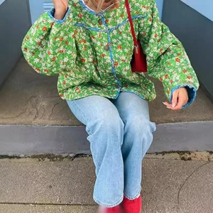 Women's green floral quilted jacket with blue trim shown in a street style pose