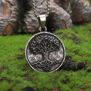 Detailed view of silver Viking Tree of Life pendant on a box chain over moss and rocks