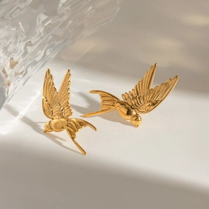 Detailed close-up of golden swallow bird earrings with a high-polished metallic finish