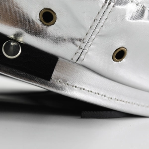 Macro shot of silver metallic fabric with brass eyelets and black faux leather trim