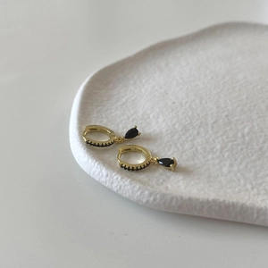 Macro shot of 925 sterling silver gold earring featuring a black zircon stone drop