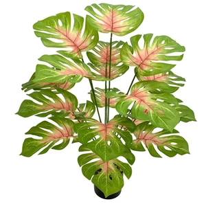 Detail of faux monstera plant with pink veined leaves in a black pot for home decor