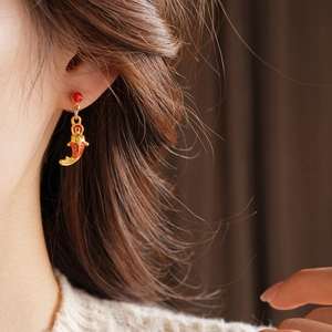 Gros plan d'une boucle d'oreille carpe koi dorée avec émail rouge sur un mannequin