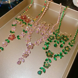 Macro detail of gold flower necklaces and earrings with vibrant zircon gemstones