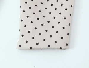 Détail de tissu à pois montrant les coutures fines et la texture tissée beige