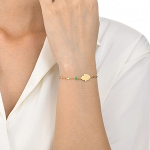 Detail of gold chain bracelet with colorful beads and Hamsa Hand charm on wrist