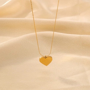 Polished 18K gold-plated stainless steel heart pendant necklace on beige silk fabric