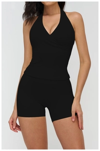Detail view of the black V-neck halter yoga top and tight sports shorts on a model