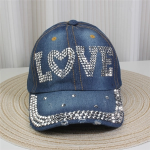 Détail de la broderie LOVE en strass scintillants sur un tissu denim bleu premium