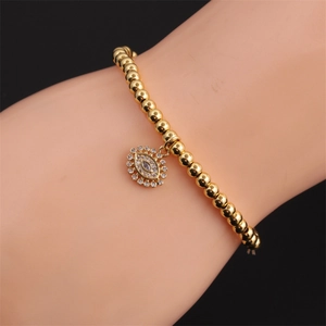 Detailed view of a gold-plated bead bracelet with a sparkling zircon evil eye charm