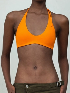 Front view of orange halter neck yoga top with deep U-neck and elastic fabric detail