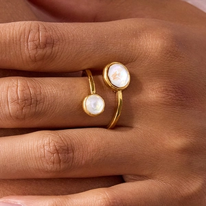 Close-up of gold stainless steel open ring featuring dual iridescent white zircons