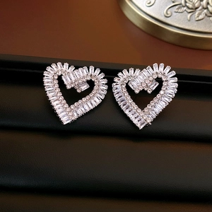 Macro detail of silver heart stud earrings with sparkling cubic zirconia on black leather